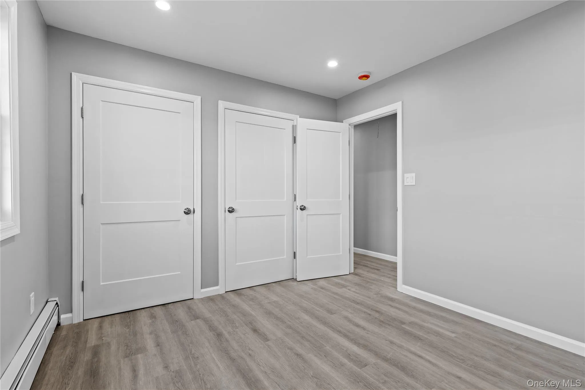 Unfurnished bedroom featuring baseboard heating, light wood-style floors, and recessed lighting Unfurnished bedroom featuring baseboard heating, light wood-style floors, and recessed lighting