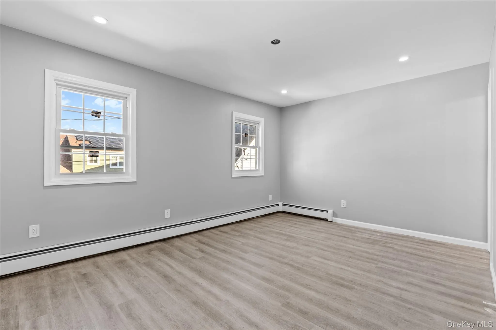 Unfurnished room with healthy amount of natural light, light wood-style floors, recessed lighting, and a baseboard heating unit Unfurnished room with healthy amount of natural light, light wood-style floors, recessed lighting, and a baseboard heating unit