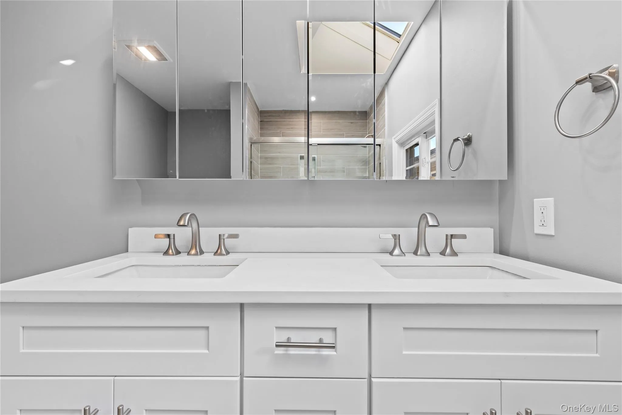 Full bathroom featuring double vanity, a skylight, and a stall shower Full bathroom featuring double vanity, a skylight, and a stall shower