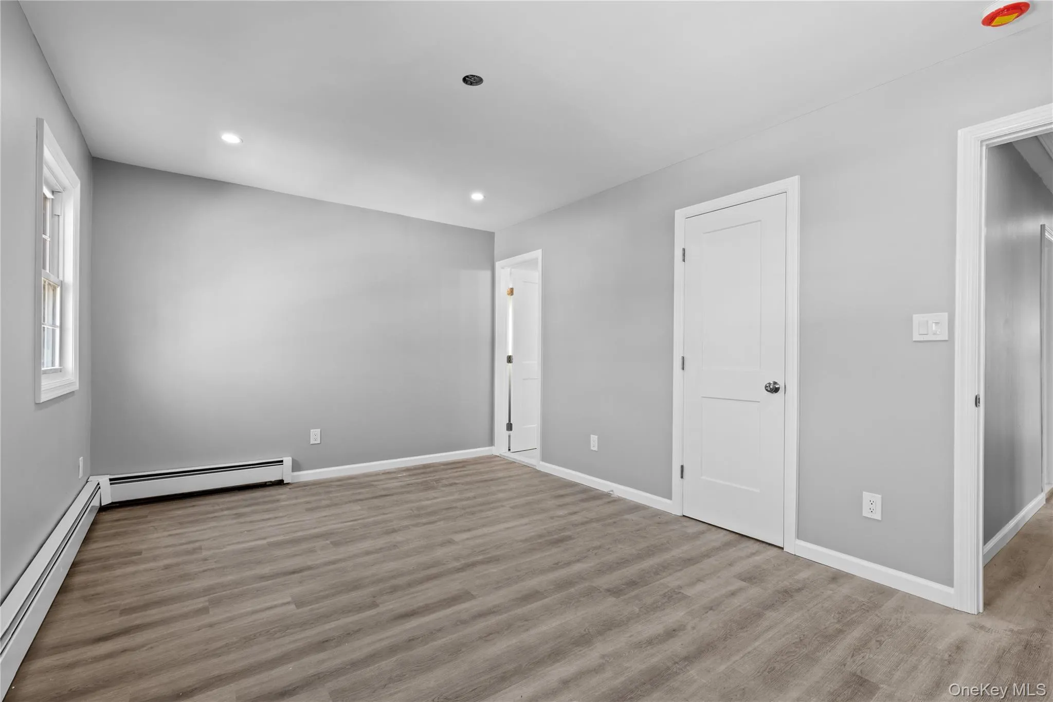 Unfurnished bedroom featuring a baseboard heating unit, recessed lighting, and wood finished floors Unfurnished bedroom featuring a baseboard heating unit, recessed lighting, and wood finished floors