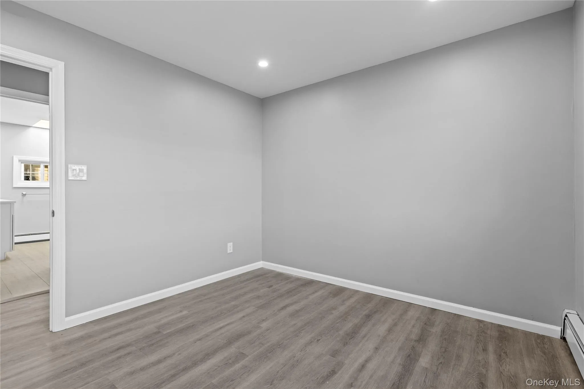 Spare room featuring wood finished floors, baseboard heating, and recessed lighting Spare room featuring wood finished floors, baseboard heating, and recessed lighting