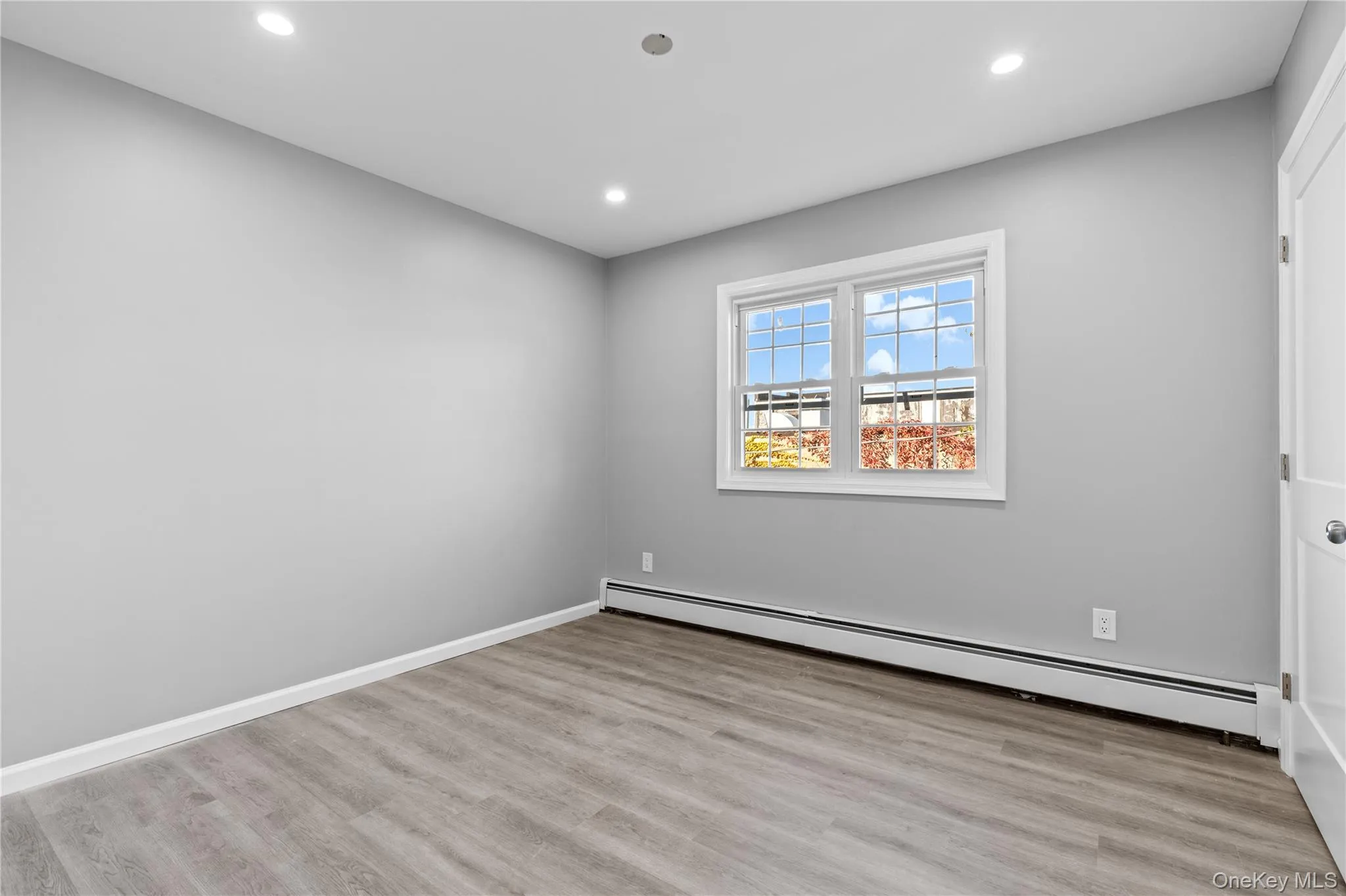 Empty room featuring baseboard heating, light wood-style flooring, and recessed lighting Empty room featuring baseboard heating, light wood-style flooring, and recessed lighting