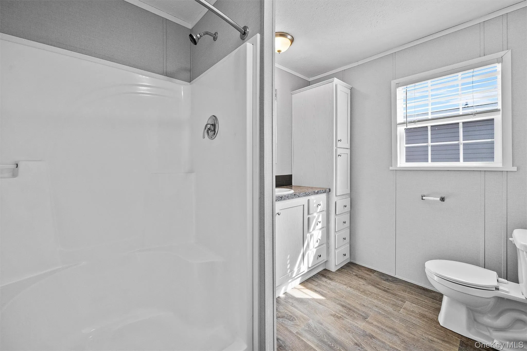 Bathroom with toilet, ornamental molding, walk in shower, and wood finished floors Bathroom with toilet, ornamental molding, walk in shower, and wood finished floors