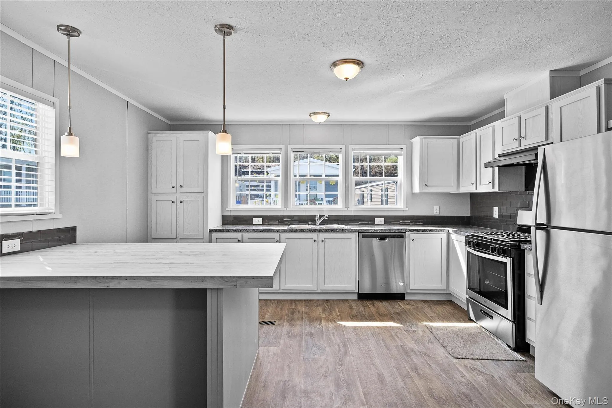 Kitchen with a peninsula, under cabinet range hood, appliances with stainless steel finishes, a sink, and wood finished floors Kitchen with a peninsula, under cabinet range hood, appliances with stainless steel finishes, a sink, and wood finished floors