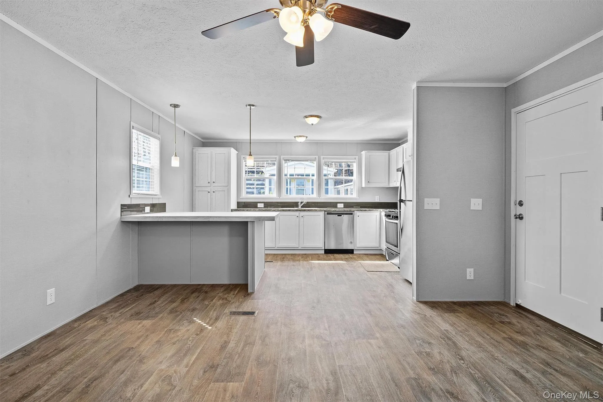 Kitchen with a peninsula, white cabinetry, a textured ceiling, and stainless steel appliances Kitchen with a peninsula, white cabinetry, a textured ceiling, and stainless steel appliances