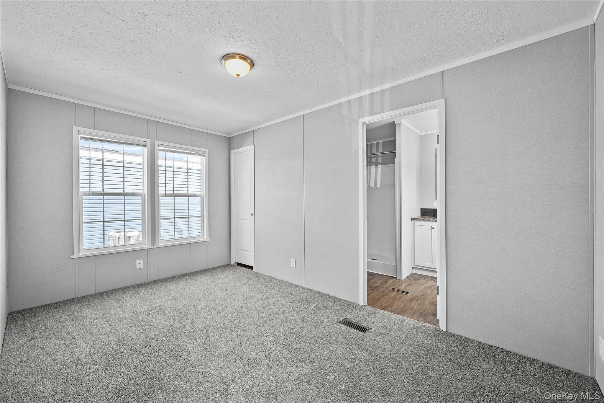 Unfurnished bedroom featuring a textured ceiling, carpet flooring, ornamental molding, and visible vents Unfurnished bedroom featuring a textured ceiling, carpet flooring, ornamental molding, and visible vents