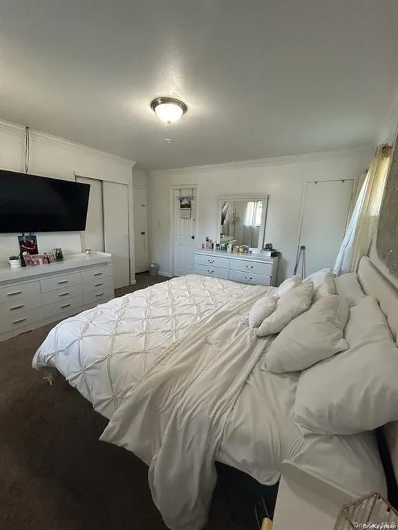 Bedroom featuring ornamental molding, dark carpet, and a closet Bedroom featuring ornamental molding, dark carpet, and a closet