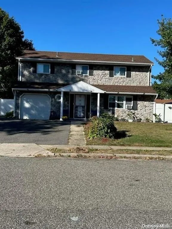 Traditional-style house featuring stone siding, driveway, and a garage Traditional-style house featuring stone siding, driveway, and a garage
