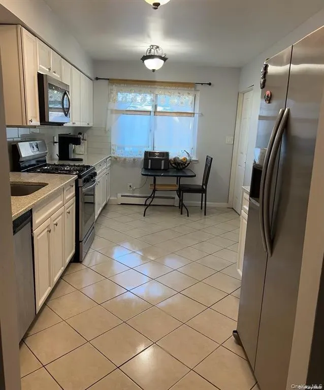 Kitchen featuring stainless steel appliances, light stone counters, tasteful backsplash, and white cabinets Kitchen featuring stainless steel appliances, light stone counters, tasteful backsplash, and white cabinets