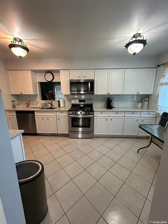 Kitchen with white cabinetry, appliances with stainless steel finishes, and light tile patterned floors Kitchen with white cabinetry, appliances with stainless steel finishes, and light tile patterned floors