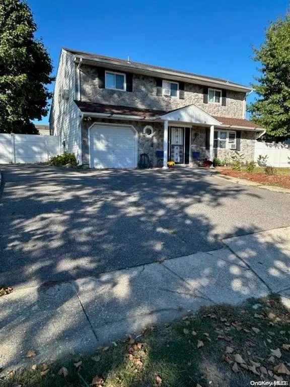 Traditional home featuring stone siding, asphalt driveway, and an attached garage Traditional home featuring stone siding, asphalt driveway, and an attached garage