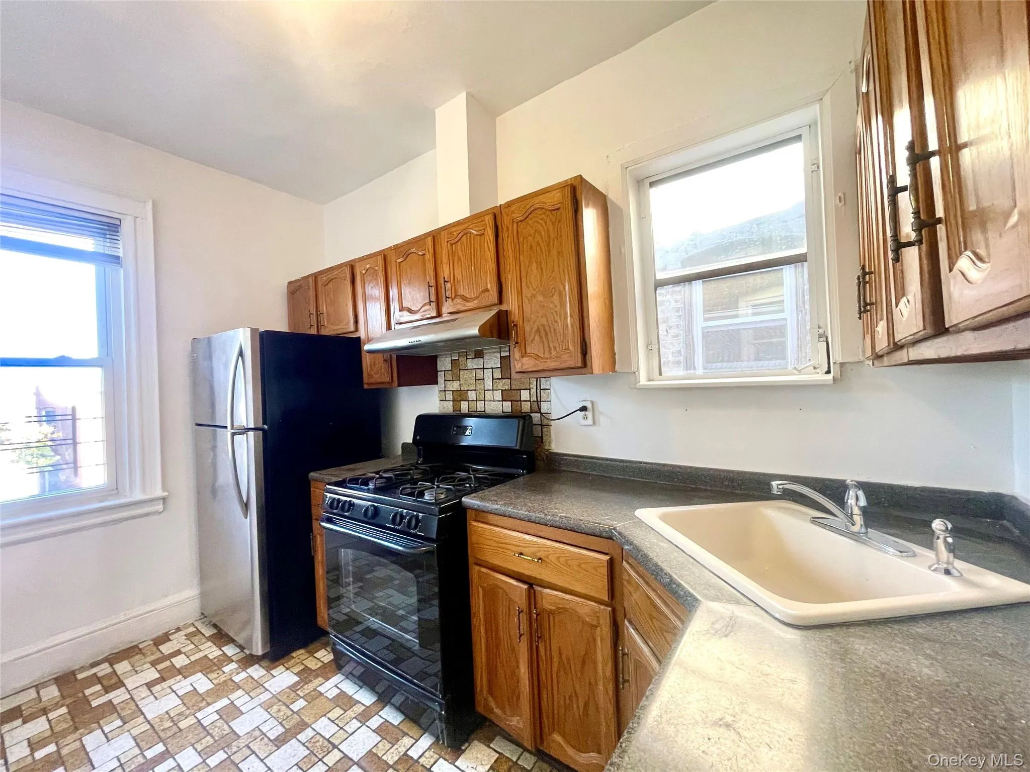 Kitchen with black gas stove, brown cabinets, dark countertops, and under cabinet range hood Kitchen with black gas stove, brown cabinets, dark countertops, and under cabinet range hood