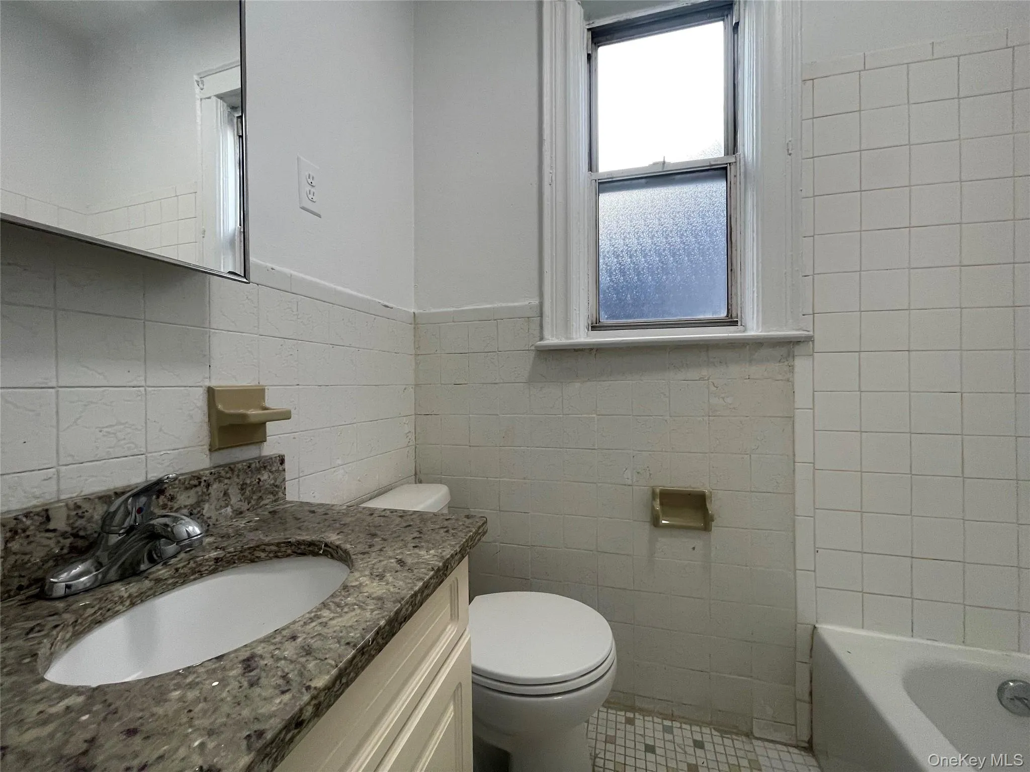 Full bathroom with tile walls, vanity, and light tile patterned floors Full bathroom with tile walls, vanity, and light tile patterned floors