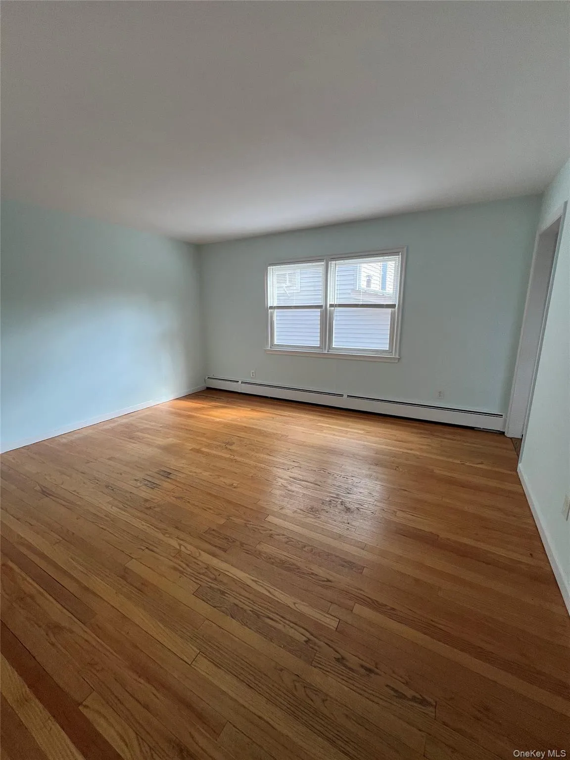 Empty room featuring light wood-style floors and baseboard heating Empty room featuring light wood-style floors and baseboard heating