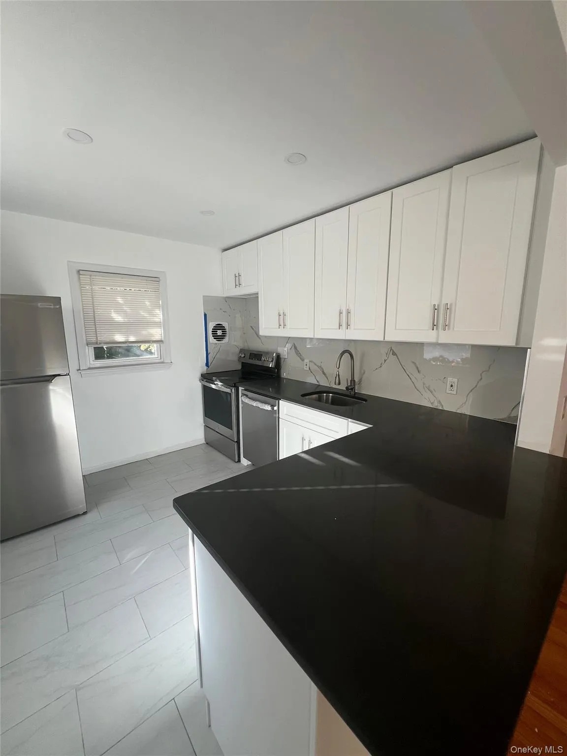 Kitchen featuring stainless steel appliances, decorative backsplash, white cabinets, and a peninsula Kitchen featuring stainless steel appliances, decorative backsplash, white cabinets, and a peninsula