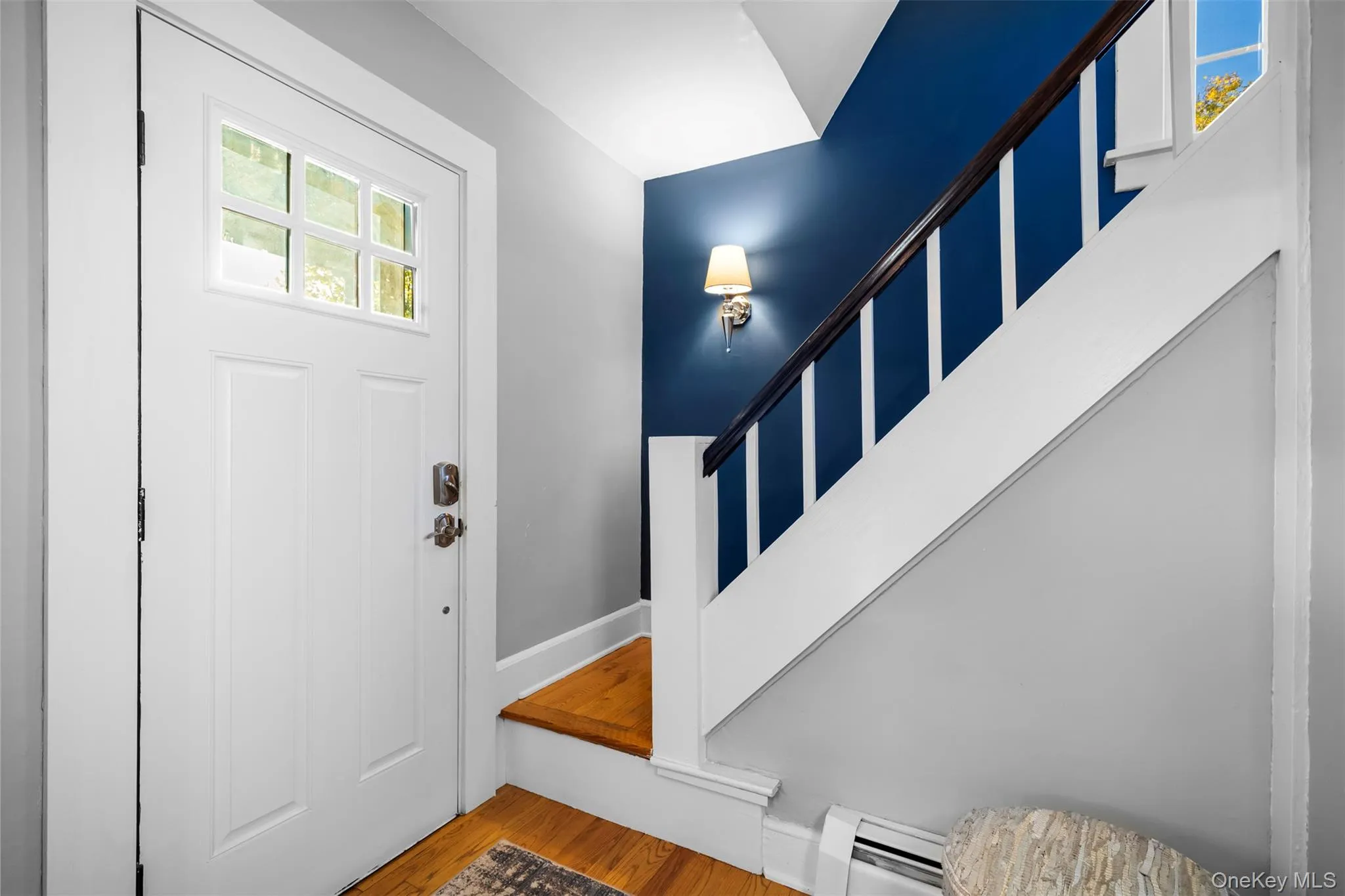 Entrance foyer with wood finished floors, stairs, and a baseboard heating unit Entrance foyer with wood finished floors, stairs, and a baseboard heating unit