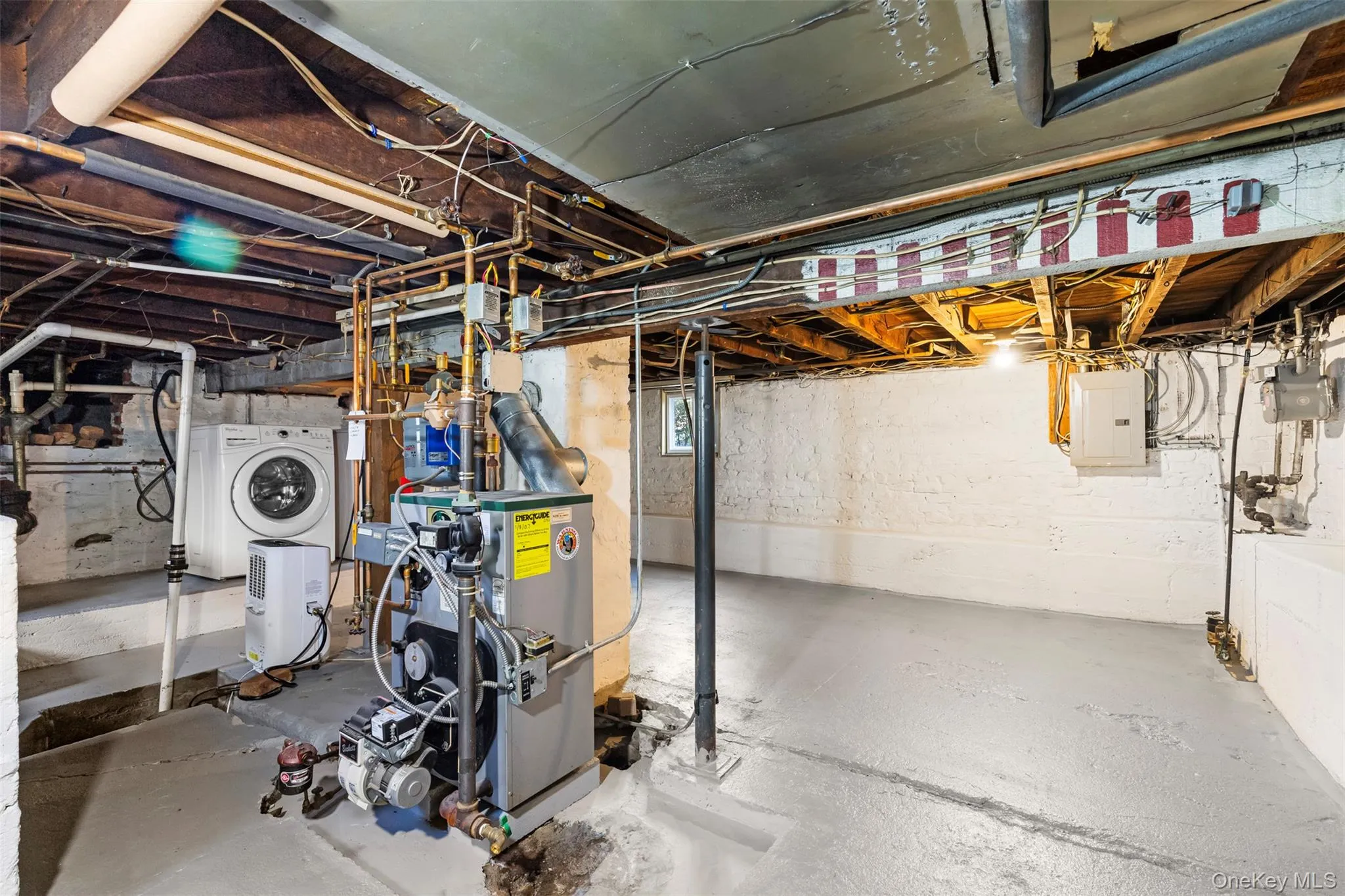 Below grade area with washer / dryer, electric panel, and a heating unit Below grade area with washer / dryer, electric panel, and a heating unit