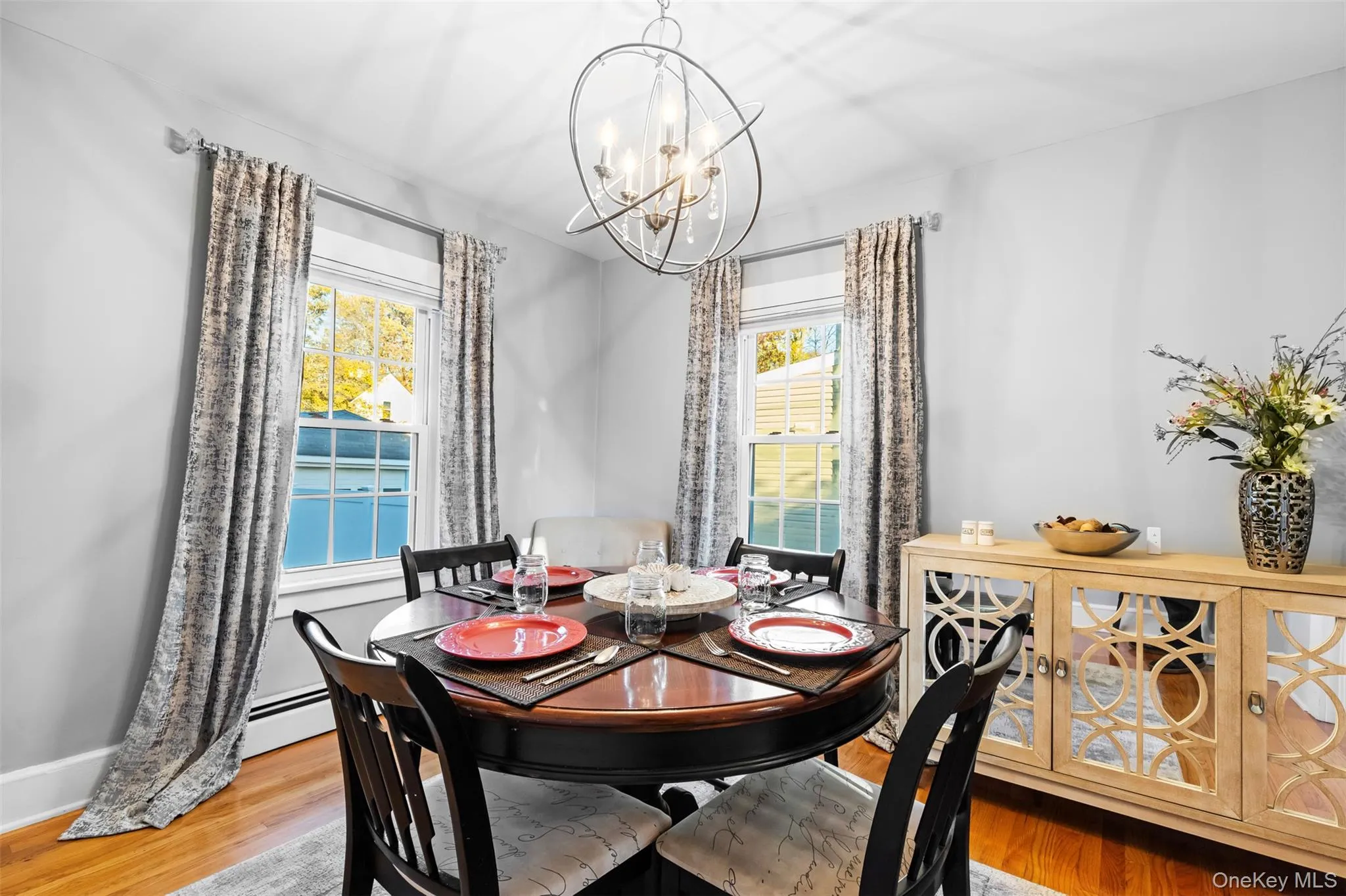 Dining space featuring wood finished floors, a baseboard radiator, and a chandelier Dining space featuring wood finished floors, a baseboard radiator, and a chandelier