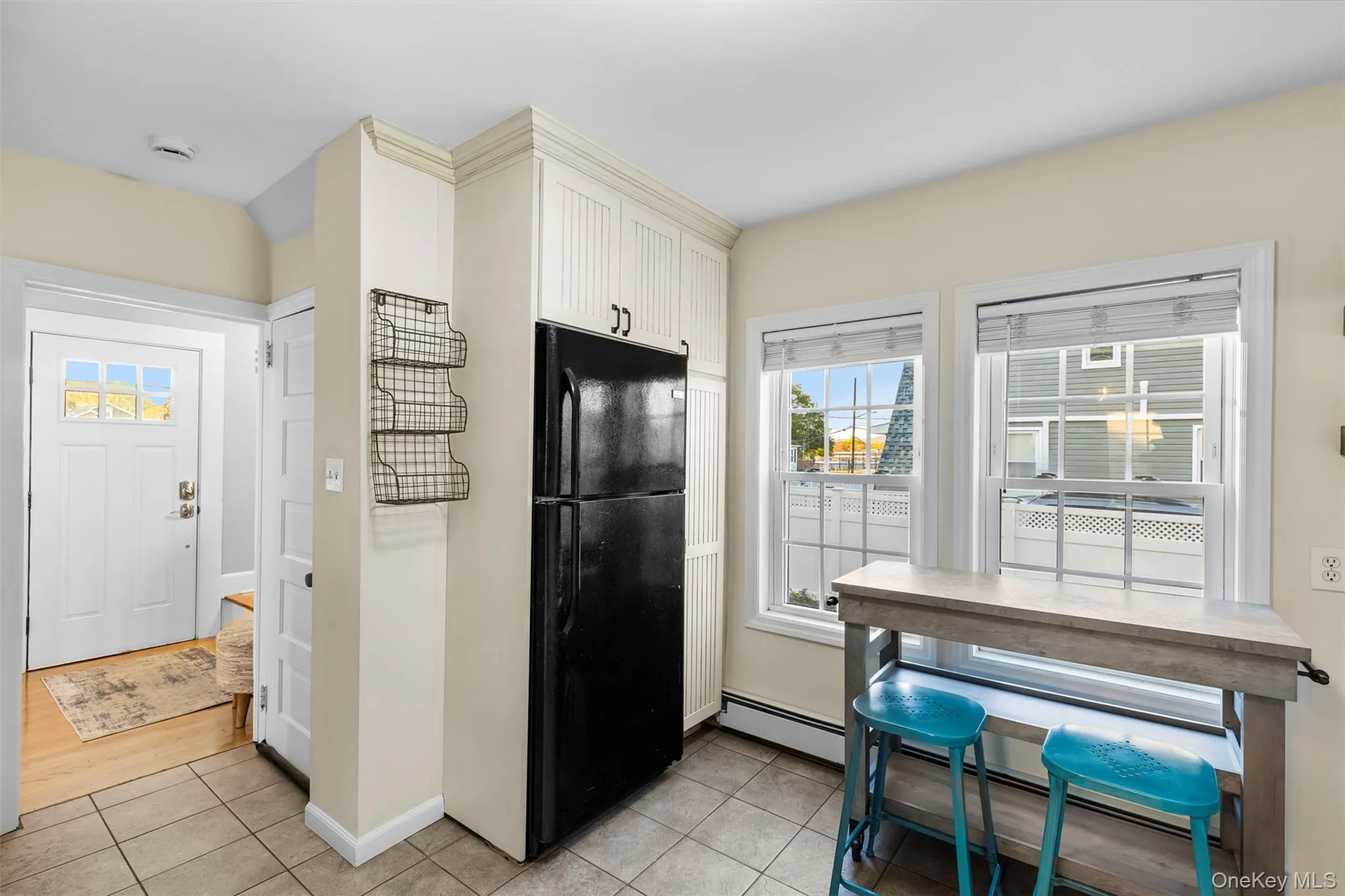 Kitchen featuring freestanding refrigerator, light tile patterned floors, and a baseboard radiator Kitchen featuring freestanding refrigerator, light tile patterned floors, and a baseboard radiator
