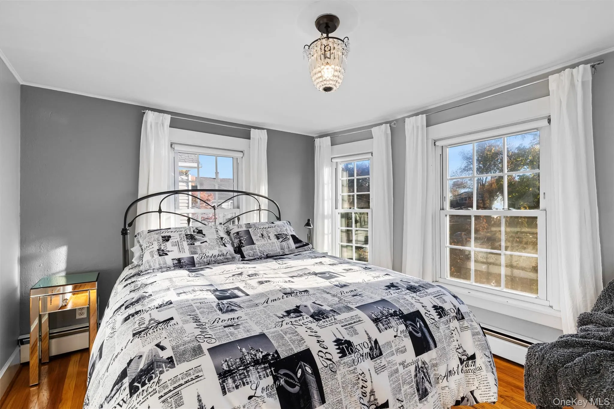 Bedroom with wood finished floors and a baseboard heating unit Bedroom with wood finished floors and a baseboard heating unit