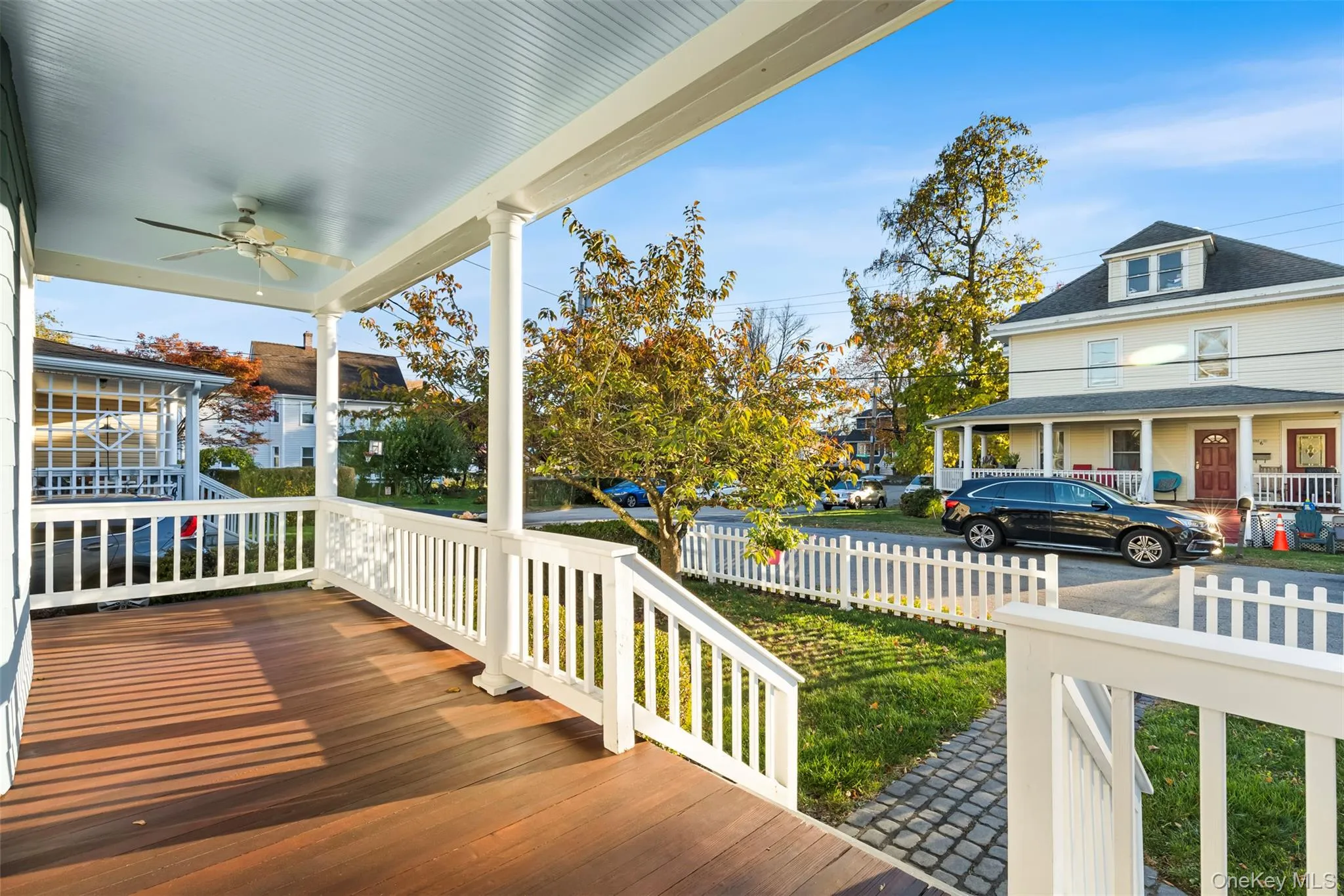 Wooden porch featuring a ceiling fan and a fenced front yard Wooden porch featuring a ceiling fan and a fenced front yard