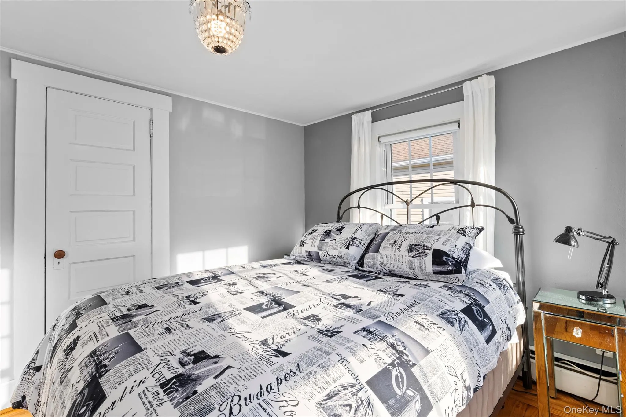 Bedroom featuring a baseboard radiator, ornamental molding, and wood finished floors Bedroom featuring a baseboard radiator, ornamental molding, and wood finished floors