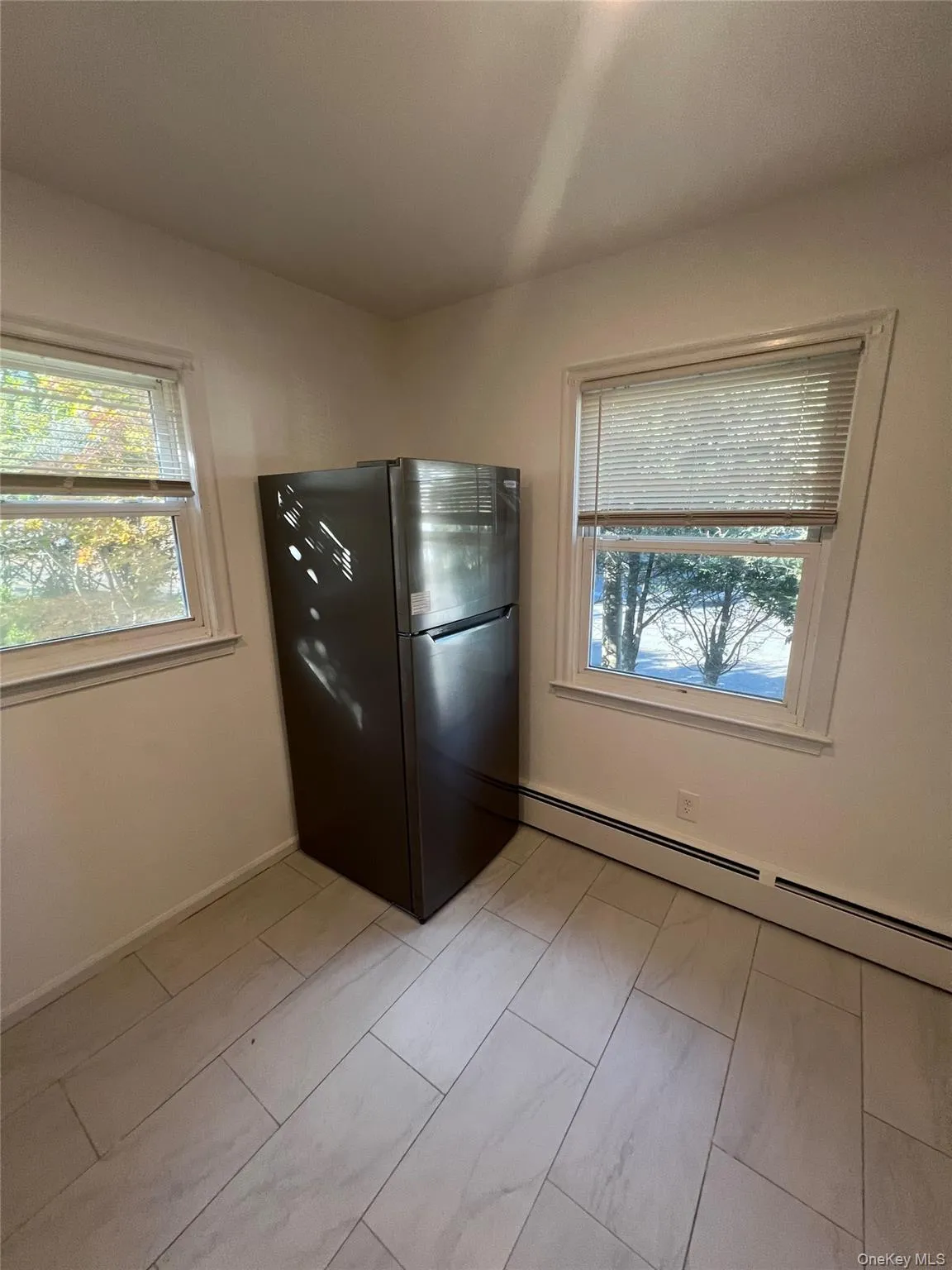 Kitchen with freestanding refrigerator, a baseboard heating unit, and plenty of natural light Kitchen with freestanding refrigerator, a baseboard heating unit, and plenty of natural light