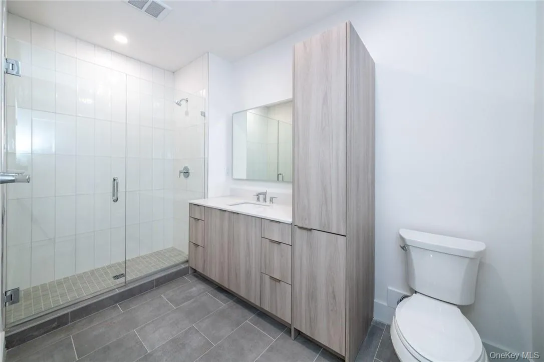 Bathroom with an enclosed shower, tile patterned flooring, toilet, and vanity Bathroom with an enclosed shower, tile patterned flooring, toilet, and vanity