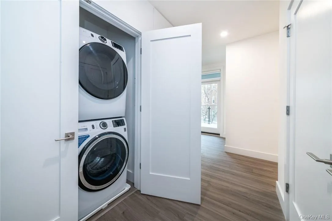 Private Laundry area featuring stacked washer / dryer and wood-type flooring Private Laundry area featuring stacked washer / dryer and wood-type flooring