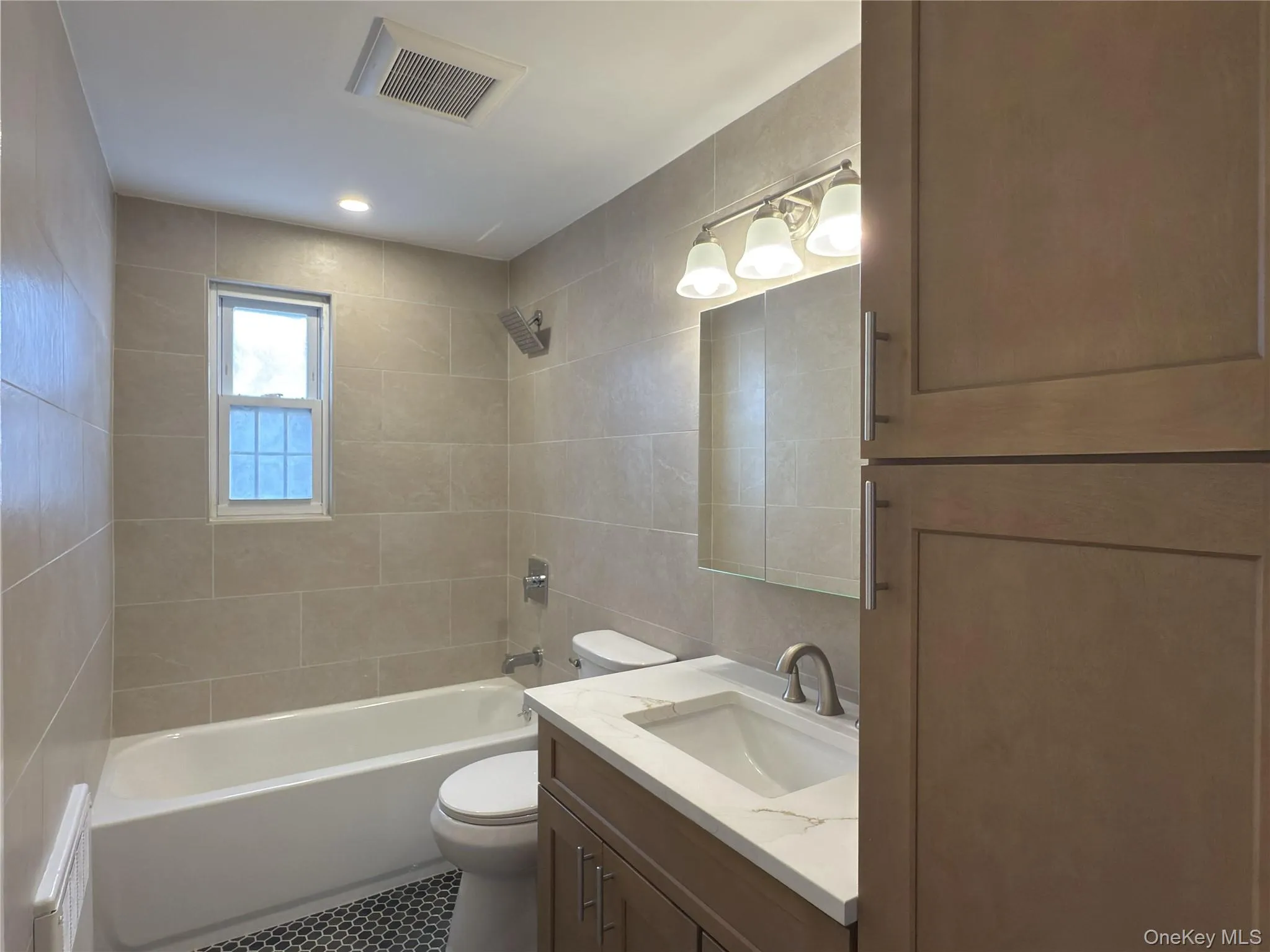 Bathroom featuring vanity, shower / bath combination, tile walls, recessed lighting, and tile patterned flooring Bathroom featuring vanity, shower / bath combination, tile walls, recessed lighting, and tile patterned flooring