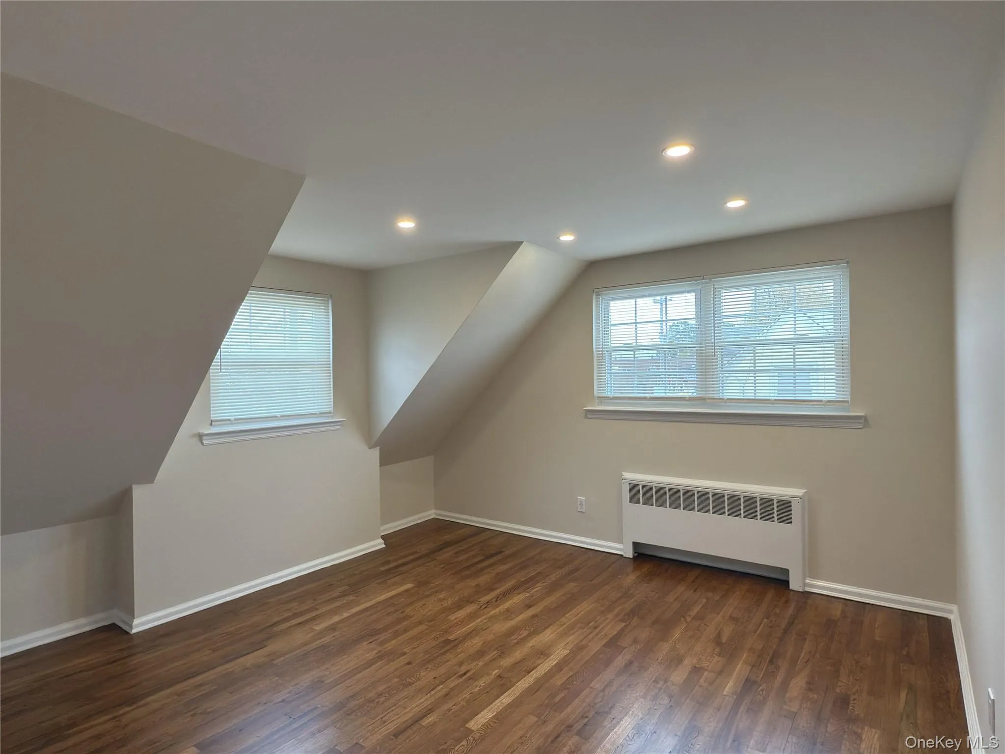 Additional living space featuring radiator heating unit, dark wood finished floors, recessed lighting, and vaulted ceiling Additional living space featuring radiator heating unit, dark wood finished floors, recessed lighting, and vaulted ceiling