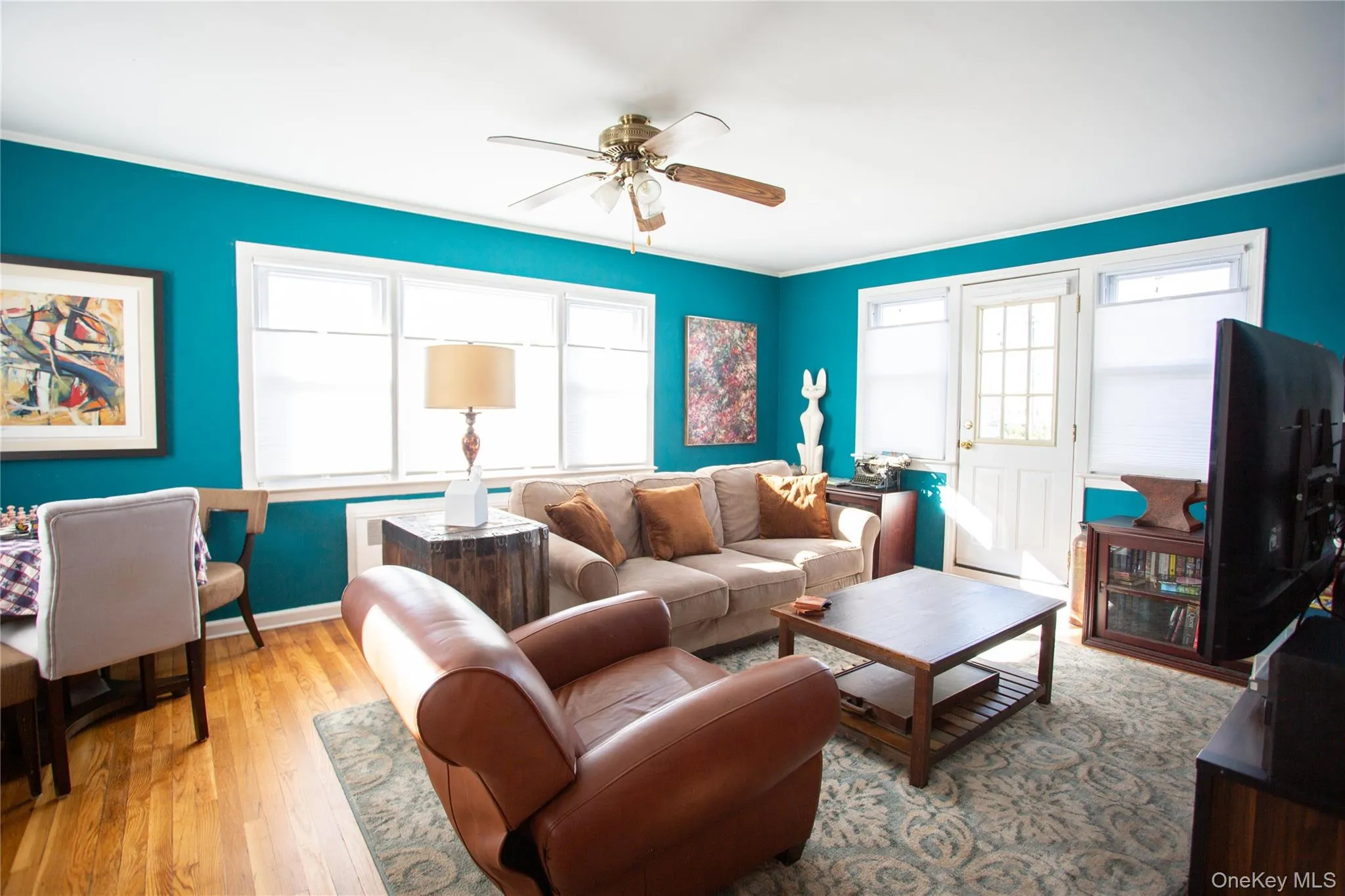 Living room featuring light wood-style floors, a ceiling fan, and crown molding Living room featuring light wood-style floors, a ceiling fan, and crown molding
