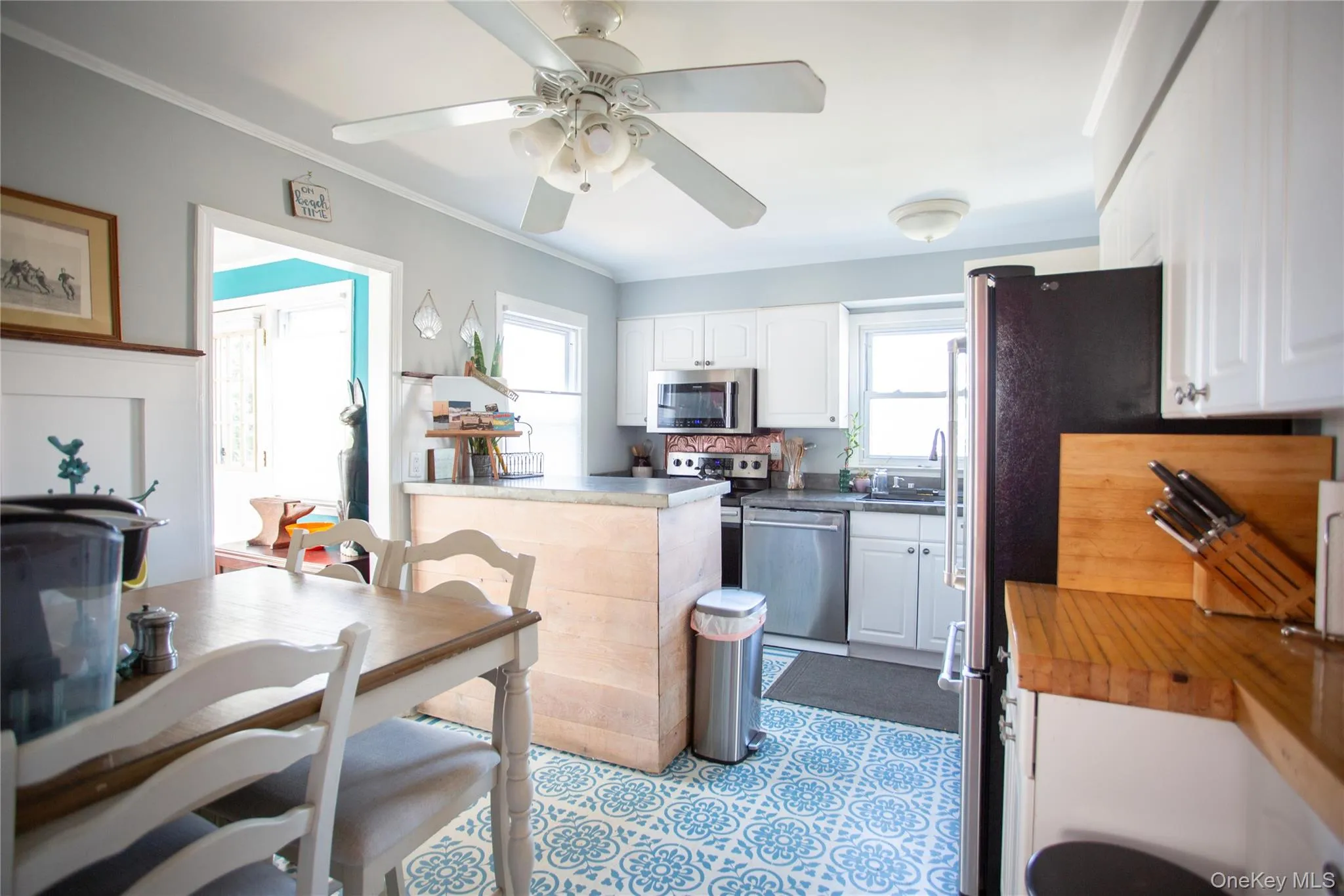 Kitchen with white cabinets, appliances with stainless steel finishes, dark countertops, ornamental molding, and ceiling fan Kitchen with white cabinets, appliances with stainless steel finishes, dark countertops, ornamental molding, and ceiling fan