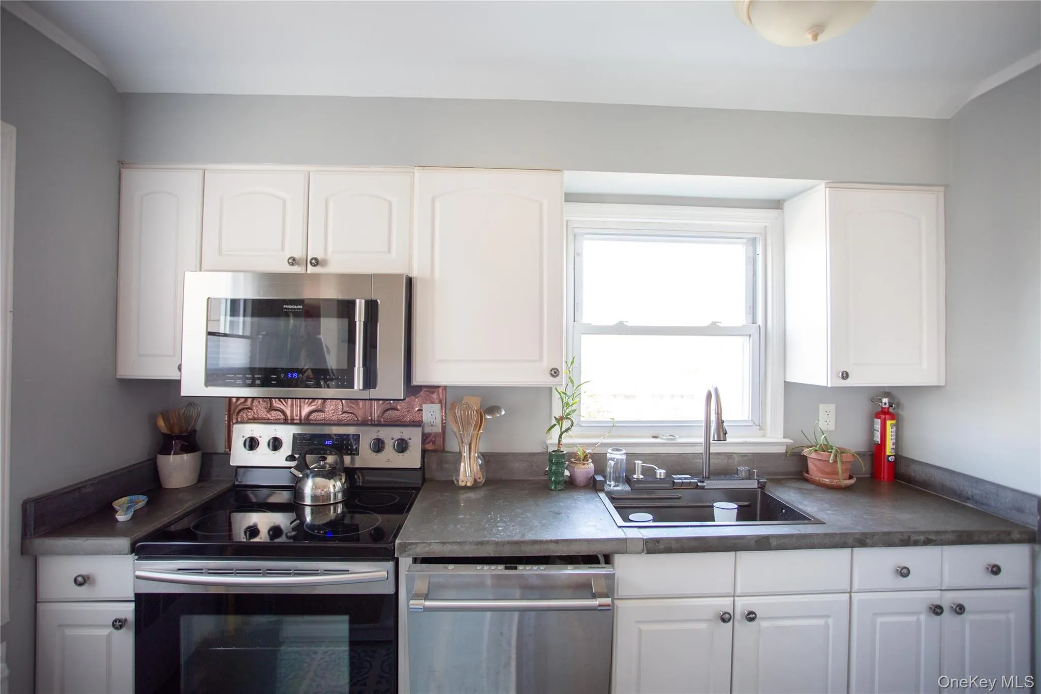 Kitchen featuring appliances with stainless steel finishes, dark countertops, and white cabinetry Kitchen featuring appliances with stainless steel finishes, dark countertops, and white cabinetry