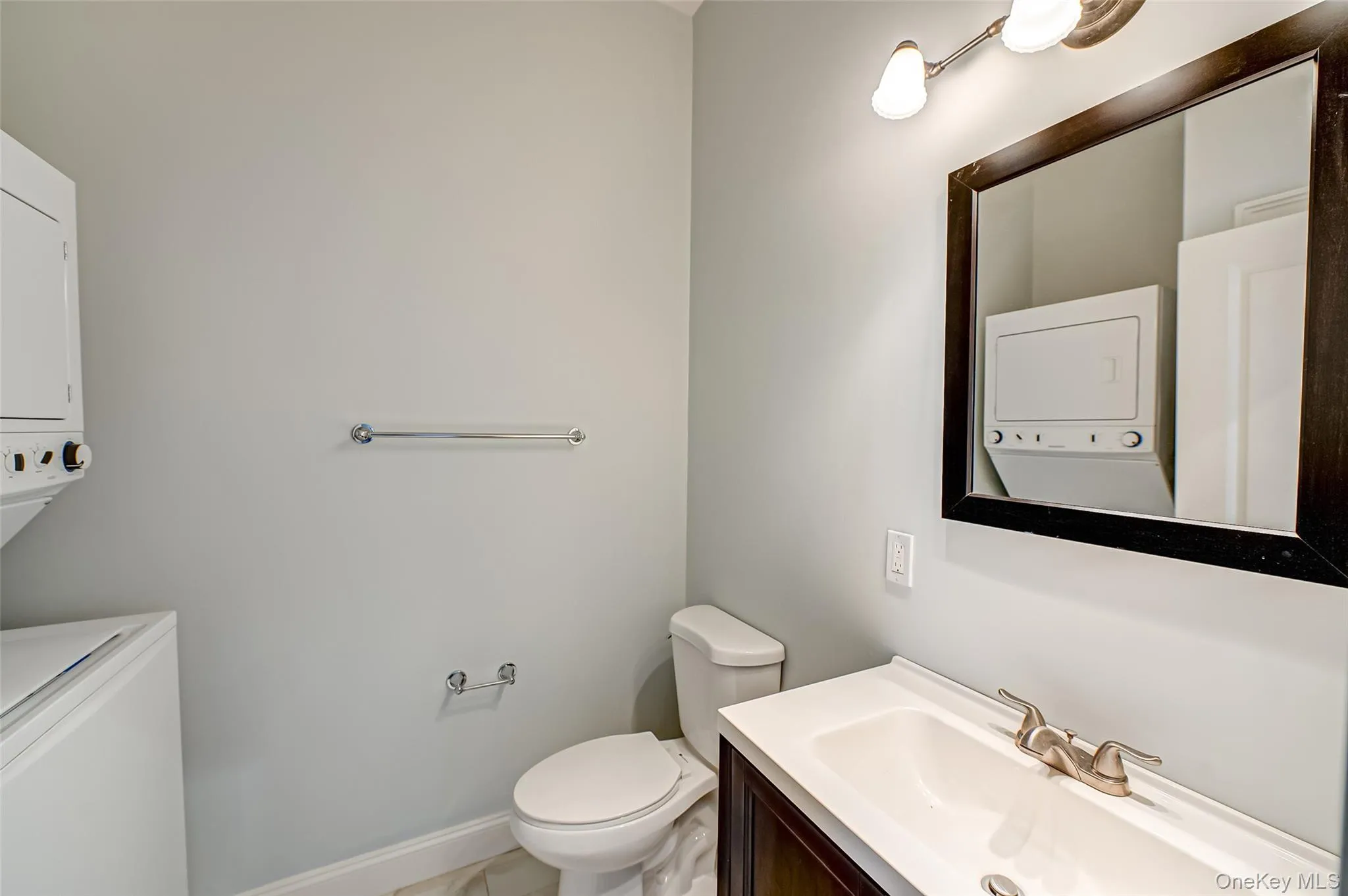 Bathroom with stacked washer / drying machine, vanity, and toilet Bathroom with stacked washer / drying machine, vanity, and toilet