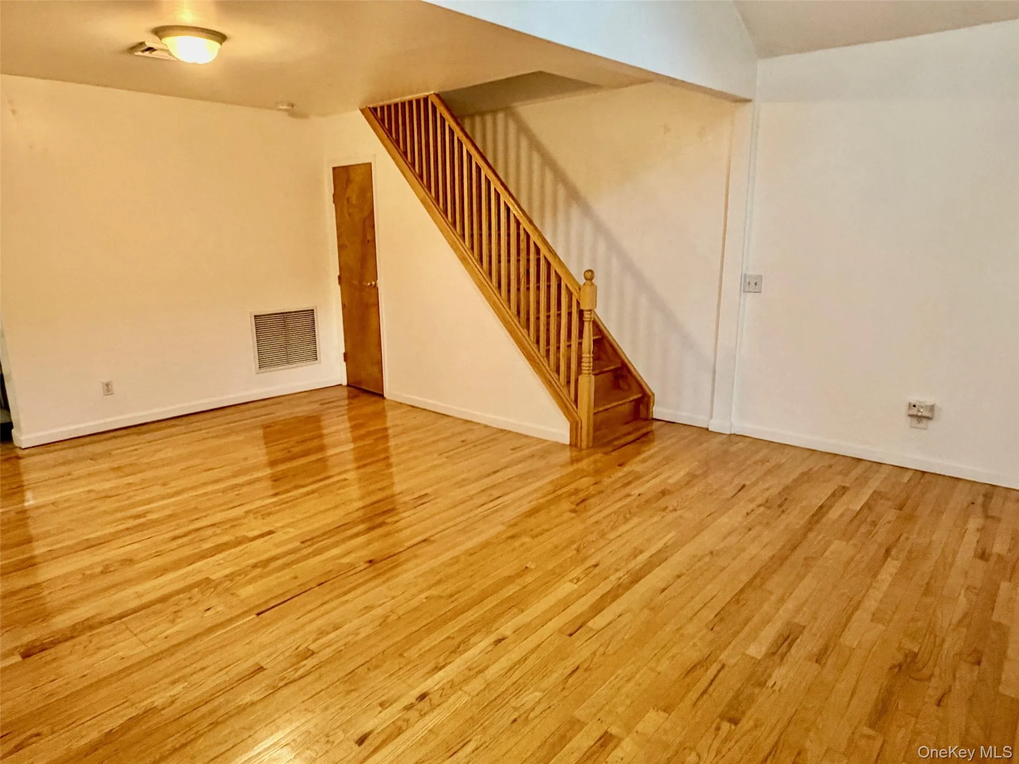 Unfurnished living room with light wood-type flooring and stairway Unfurnished living room with light wood-type flooring and stairway