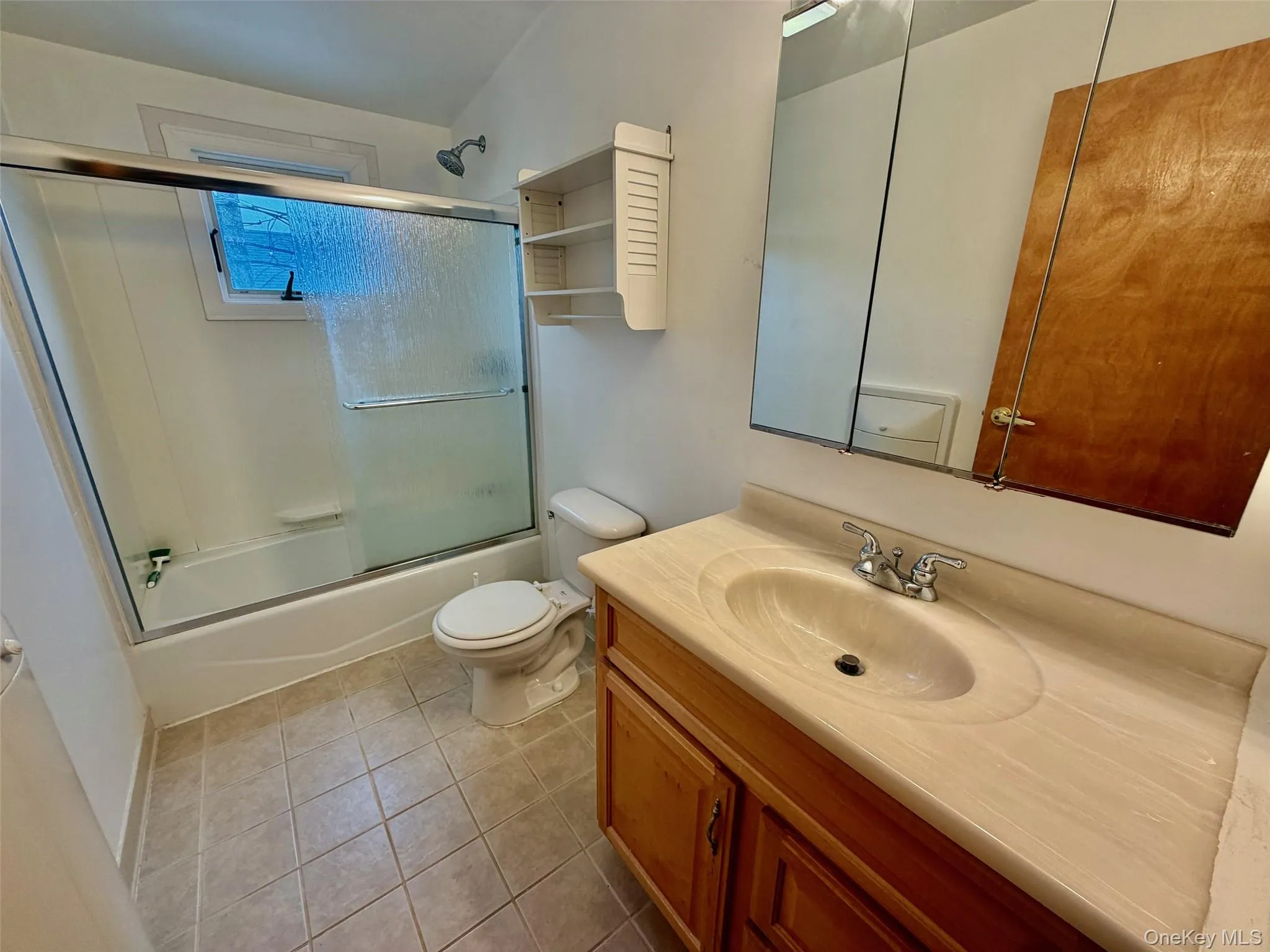 Bathroom with vanity, light tile patterned floors, and combined bath / shower with glass door Bathroom with vanity, light tile patterned floors, and combined bath / shower with glass door