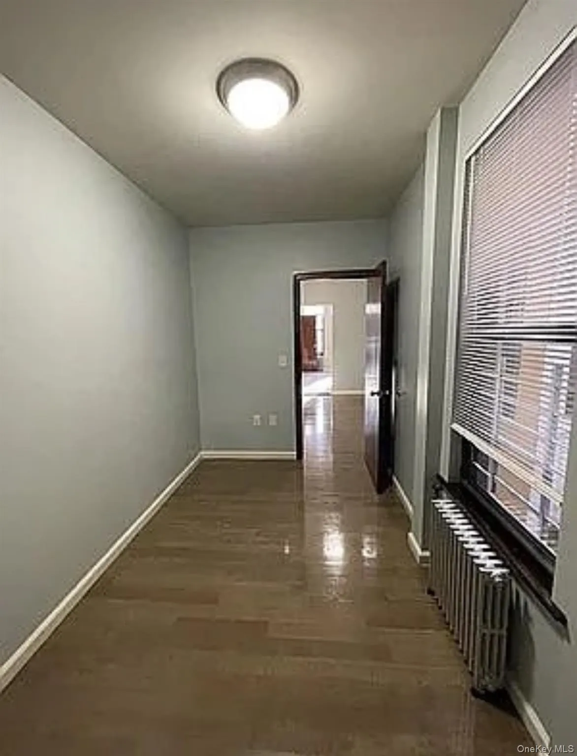 Hall featuring radiator heating unit and dark wood-style flooring Hall featuring radiator heating unit and dark wood-style flooring