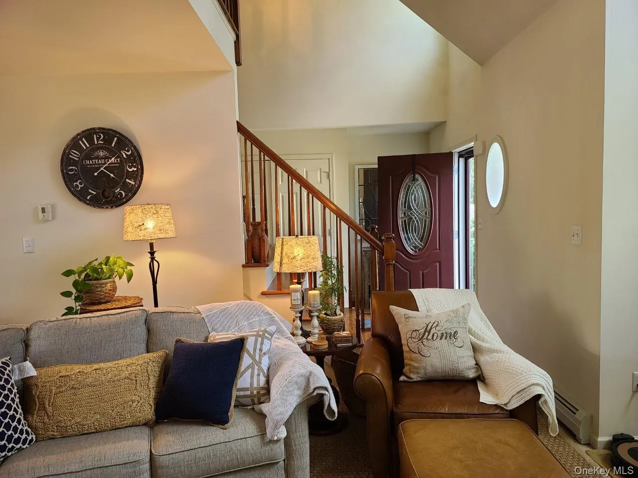 Living room featuring baseboard heating, stairs, and a high ceiling Living room featuring baseboard heating, stairs, and a high ceiling