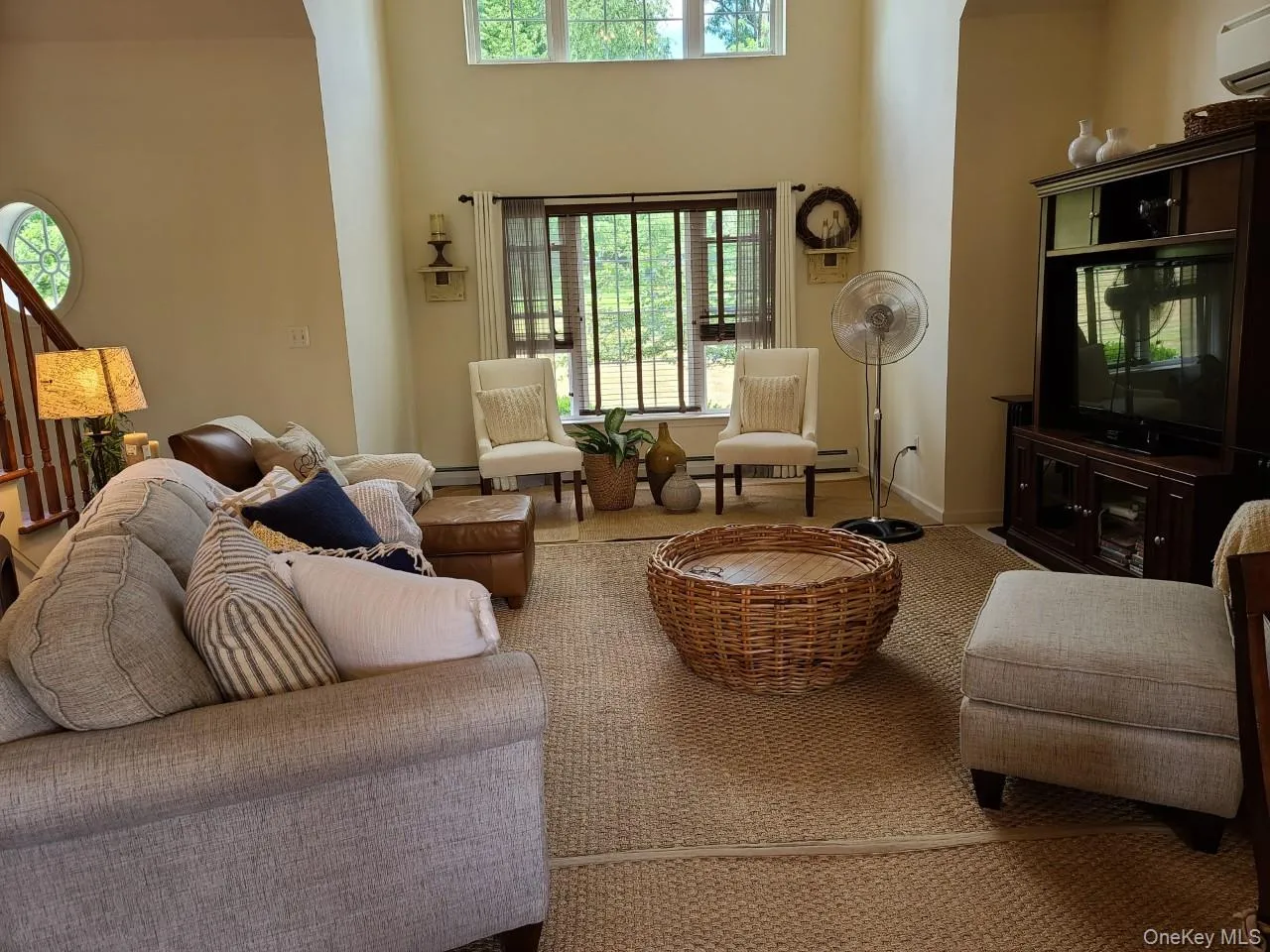 Living room with a towering ceiling, a wall mounted air conditioner, and carpet Living room with a towering ceiling, a wall mounted air conditioner, and carpet