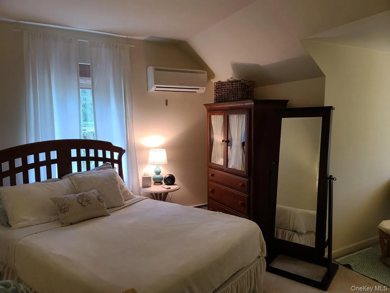 Carpeted bedroom featuring vaulted ceiling and a wall mounted AC Carpeted bedroom featuring vaulted ceiling and a wall mounted AC