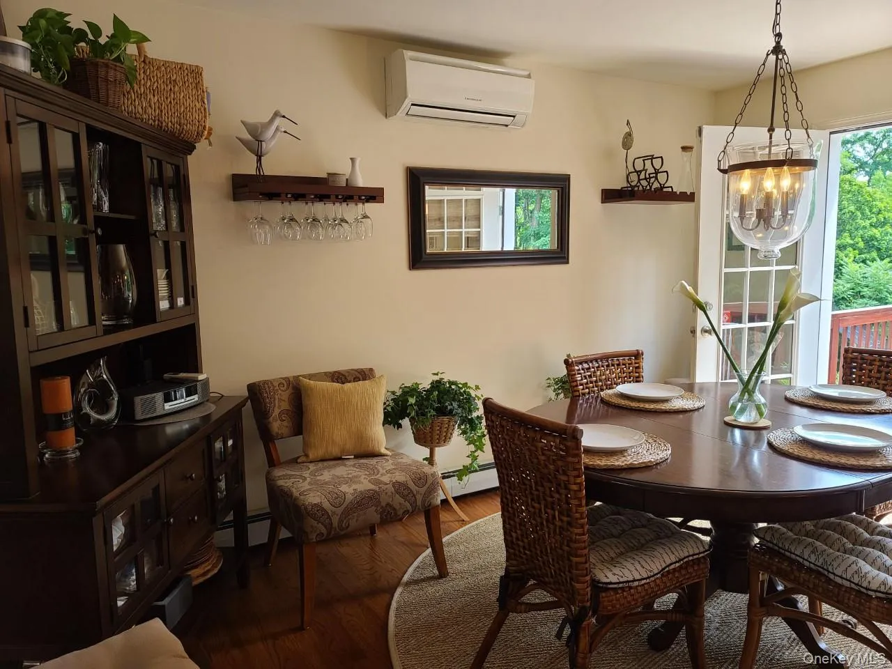 Dining space with wood finished floors, a chandelier, a wall mounted air conditioner, and a baseboard heating unit Dining space with wood finished floors, a chandelier, a wall mounted air conditioner, and a baseboard heating unit