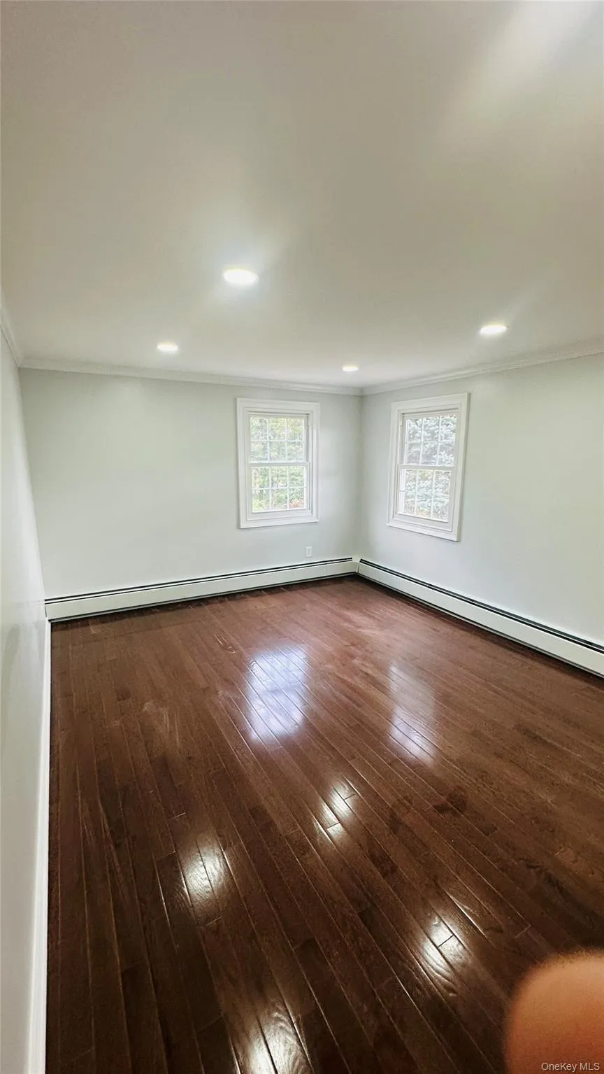Spare room featuring crown molding, dark wood-style floors, plenty of natural light, baseboard heating, and recessed lighting Spare room featuring crown molding, dark wood-style floors, plenty of natural light, baseboard heating, and recessed lighting
