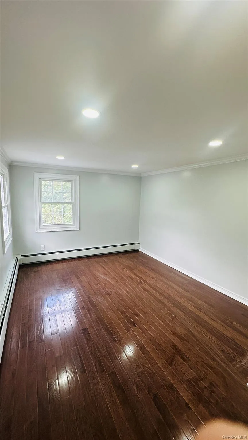 Spare room featuring crown molding, dark wood-type flooring, recessed lighting, and a baseboard radiator Spare room featuring crown molding, dark wood-type flooring, recessed lighting, and a baseboard radiator