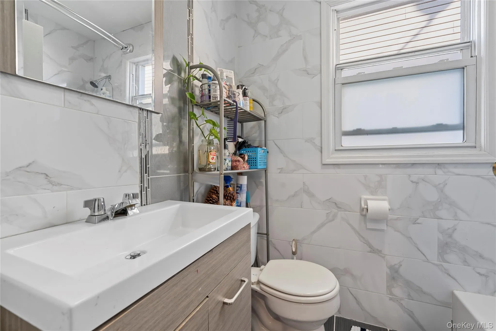 Full bathroom with vanity, a marble finish shower, and tile walls Full bathroom with vanity, a marble finish shower, and tile walls