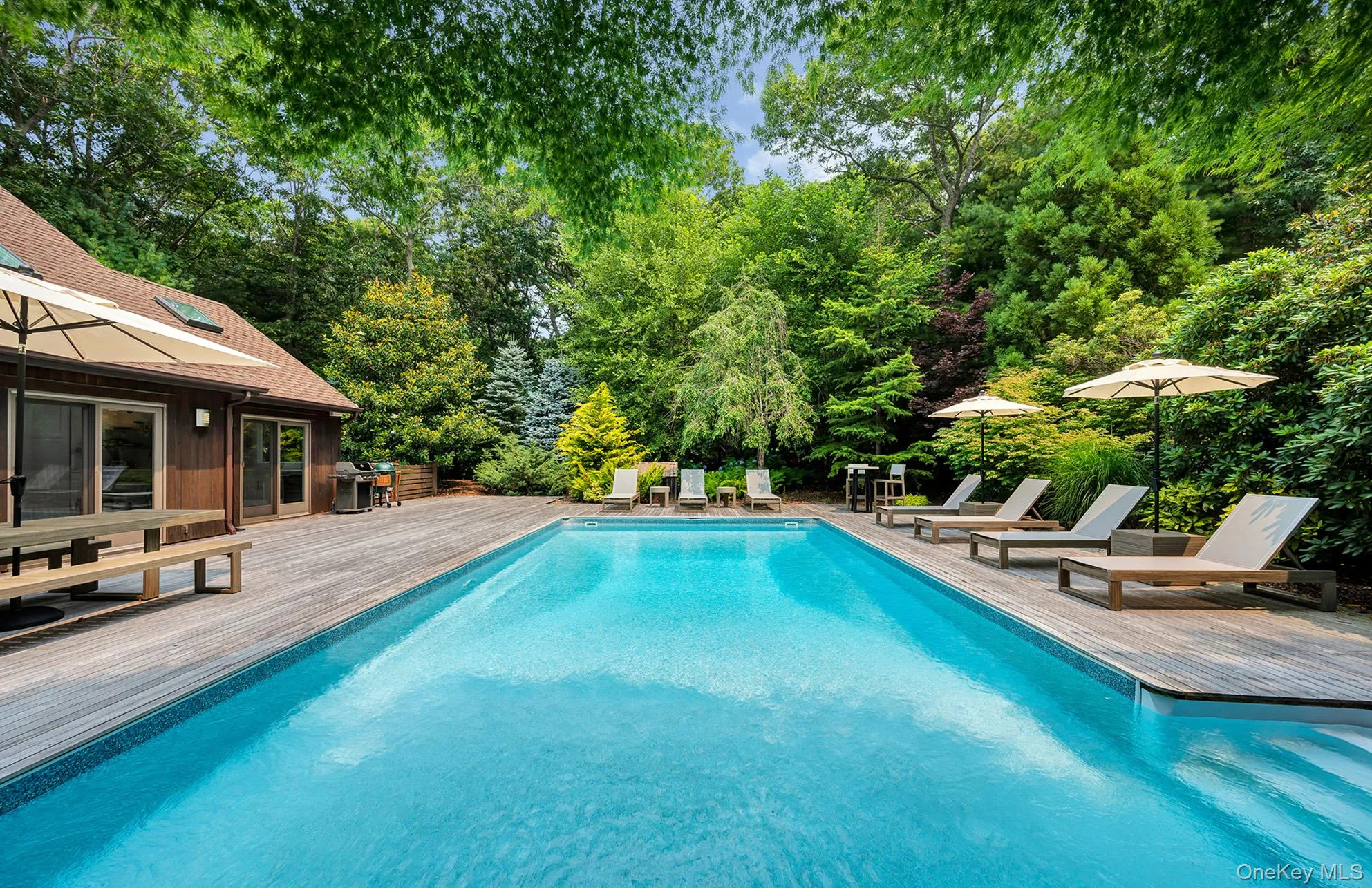 Swimming pool with view of wooded area, area for grilling, a patio area, and a wooden deck Swimming pool with view of wooded area, area for grilling, a patio area, and a wooden deck
