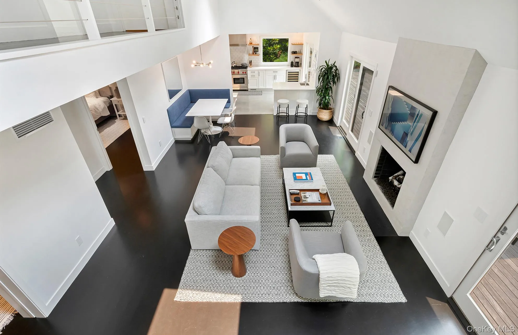 Living room featuring dark wood-type flooring, a high ceiling, beverage cooler, and a fireplace Living room featuring dark wood-type flooring, a high ceiling, beverage cooler, and a fireplace