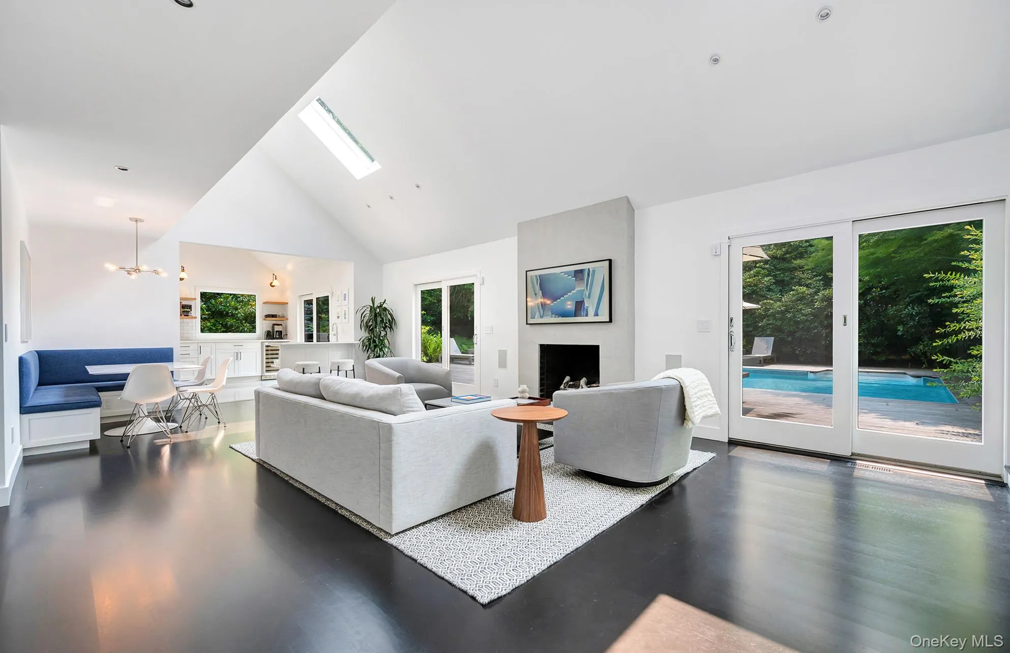 Living room with high vaulted ceiling, a skylight, wood finished floors, and a chandelier Living room with high vaulted ceiling, a skylight, wood finished floors, and a chandelier