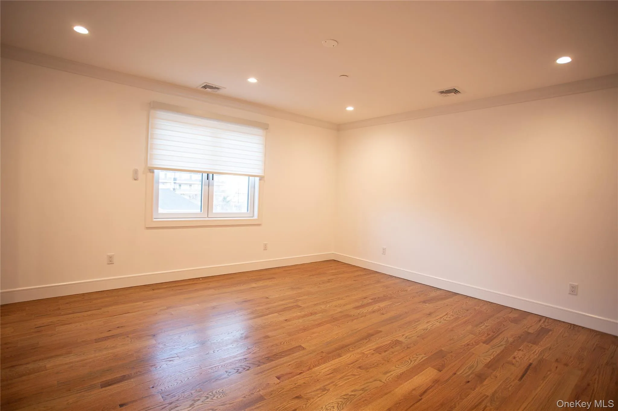 Empty room featuring ornamental molding, recessed lighting, and light wood-style flooring Empty room featuring ornamental molding, recessed lighting, and light wood-style flooring