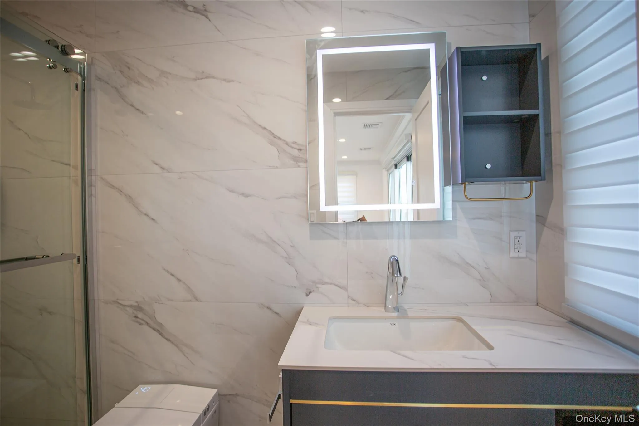 Bathroom with vanity, a marble finish shower, and tile walls Bathroom with vanity, a marble finish shower, and tile walls